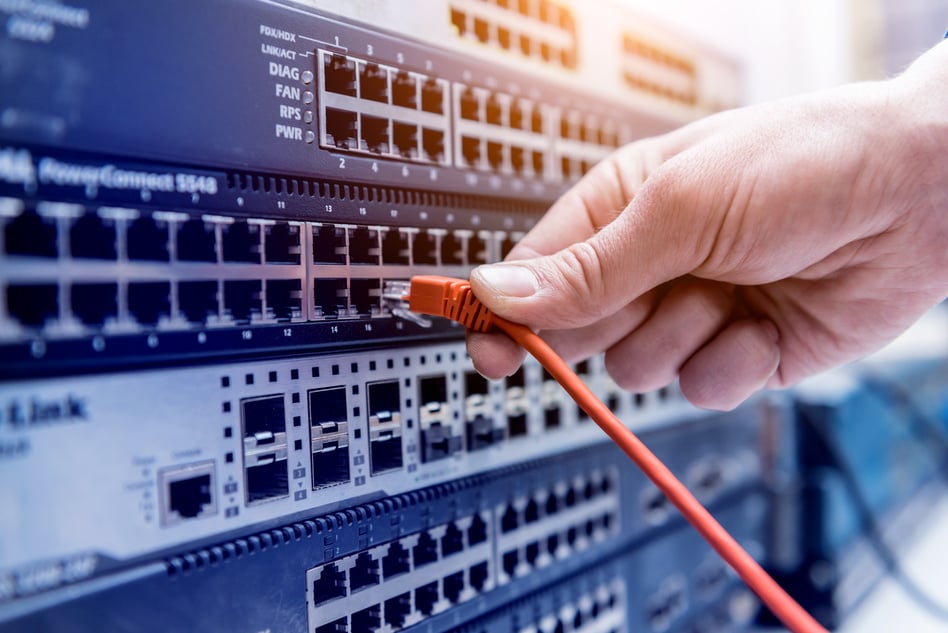 Network engineer working in server room. Connecting network cables to switches